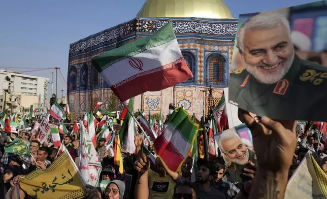 Demonstrators wave Iranian flags and hold posters of the late Iranian Revolutionary Guard Gen. Qassem Soleimani, who was killed in a U.S. strike in Iraq in 2020, in front of a model of Jerusalem's Dome of the Rock mosque during a rally marking the Muslim Shiite holiday of Eid al-Ghadir, which commemorates the Prophet Muhammad naming his successor, Ali, who is revered as the first Shiite imam, in Tehran, Iran, Saturday, June 14, 2025. (AP Photo/Vahid Salemi)