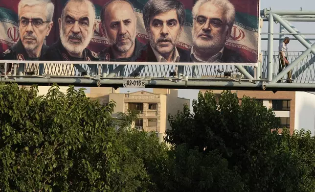 A man walks past a billboard displaying images of top Iranian commanders and scientists killed in Israeli strikes early Friday, in Tehran, Iran, Friday, June 13, 2025. (AP Photo/Vahid Salemi)