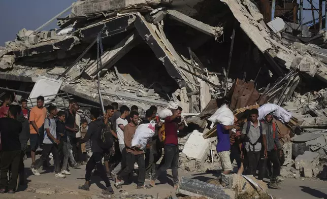 Palestinians carry humanitarian aid packages distributed by the Gaza Humanitarian Foundation operated by the U.S.-backed organization in Khan Younis, southern Gaza Strip, Thursday, June 26, 2025. (AP Photo/Abdel Kareem Hana)