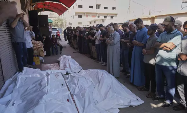 Palestinians pray over the bodies of people who were killed during an Israeli strike, at their funeral in Deir al-Balah, Gaza Strip, Wednesday, June 25, 2025. (AP Photo/Abdel Kareem Hana)