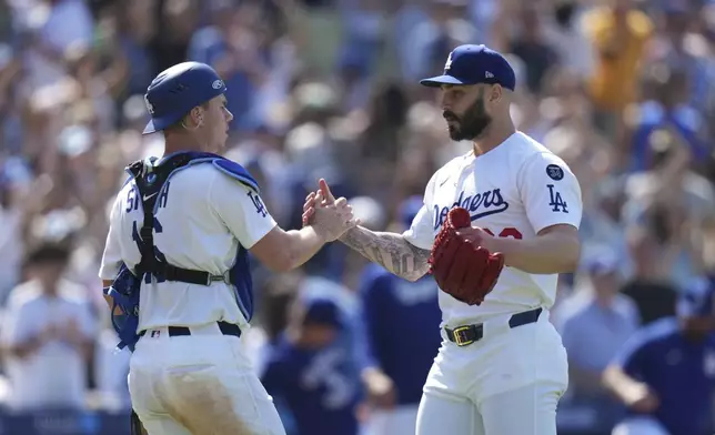 Los Angeles Dodgers catcher Will Smith (16) and pitcher Tanner Scott (66) celebrate the team's 6-5 win against the New York Mets in a baseball game Thursday, June 5, 2025, in Los Angeles. (AP Photo/Jae C. Hong)