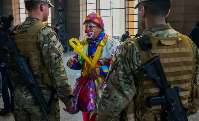 A clown talks with soldiers before voting in primary elections held by the Unidos por Chile coalition to choose the ruling party's candidate for the upcoming presidential election, in Santiago, Chile, Sunday, June 29, 2025. (AP Photo/Esteban Felix)
