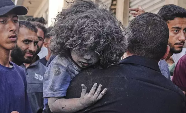 A Palestinian man carries a wounded child after an Israeli strike on a residential building in Gaza City, Friday, June 27, 2025. (AP Photo/Jehad Alshrafi)