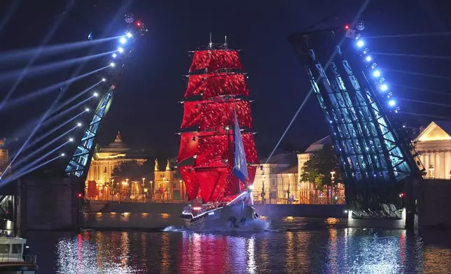 A brig with scarlet sails floats through Dvortsovy (Palace) drawbridge on the Neva River during a rehearsal for the Scarlet Sails festivities marking school graduation in St. Petersburg, Russia, early Saturday, June 28, 2025. (AP Photo/Dmitri Lovetsky)