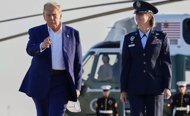 President Donald Trump, left, escorted by Air Force Col. Angela F. Ochoa, Commander, 89th Airlift Wing, walks from Marine One to board Air Force One, Tuesday, June 24, 2025, at Joint Base Andrews, Md. (AP Photo/Alex Brandon)