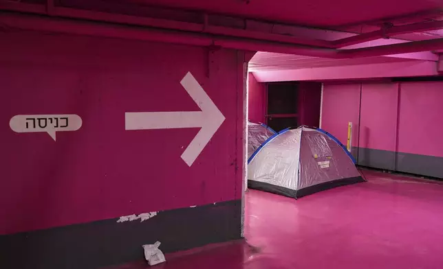 Sleeping tents are placed in an underground parking garage used as a shelter from missile strikes from Iran, in Tel Aviv, Israel, Saturday, June 21, 2025. Writing in Hebrew reads "Entry". (AP Photo/Bernat Armangue)