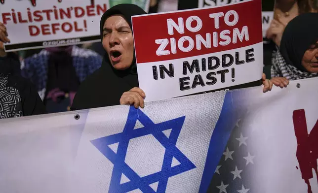 People shout slogans during an anti Israel protest in Istanbul, Turkey, Saturday, June 21, 2025. The board on the left reads in Turkish: "Get out of Palestine". (AP Photo/Francisco Seco)