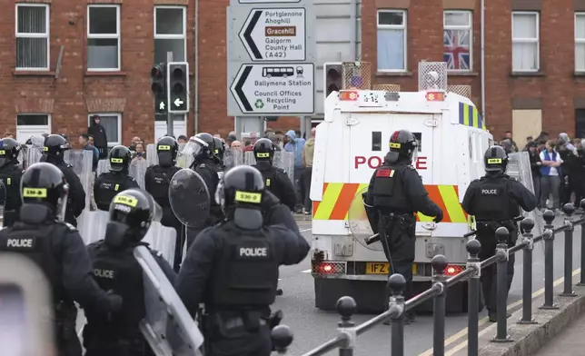 Police in riot gear form a protective line as a crowd gathers in Ballymena, Northern Ireland, protesting over an alleged sexual assault in the Co Antrim town, Wednesday, June 11, 2025. (AP Photo/Peter Morrison)