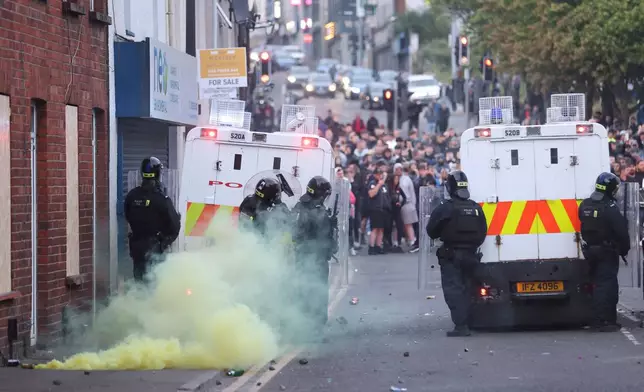 A yellow flare smokes after being thrown at the police by the crowd in Ballymena, Northern Ireland, as people protest over an alleged sexual assault in the Co Antrim town, Wednesday, June 11, 2025. (AP Photo/Peter Morrison)