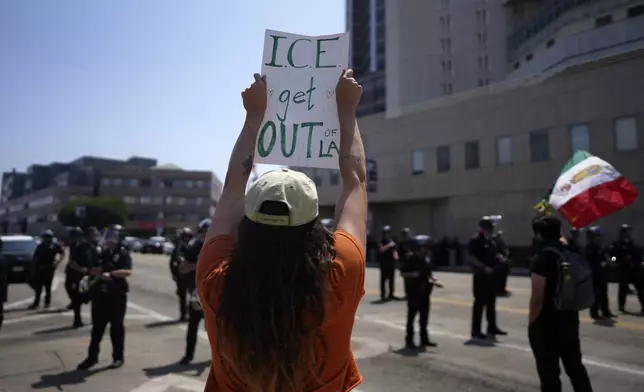 A protester holds a sign up in front of the Metropolitan Detention Center in downtown Los Angeles on Monday, June 9, 2025. (AP Photo/Eric Thayer)
