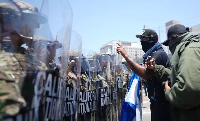Protesters confront a line of U.S. National Guard in the metropolitan detention center of downtown Los Angeles, Sunday, June 8, 2025, following last night's immigration raid protest. (AP Photo/Eric Thayer)