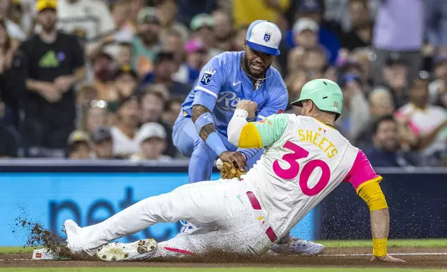 San Diego Padres' Gavin Sheets (30) slides safe into third, beating the tag from Kansas City Royals third baseman Maikel Garcia, in the seventh inning of a baseball game, Friday, June 20, 2025, in San Diego. (AP Photo/Tony Ding)