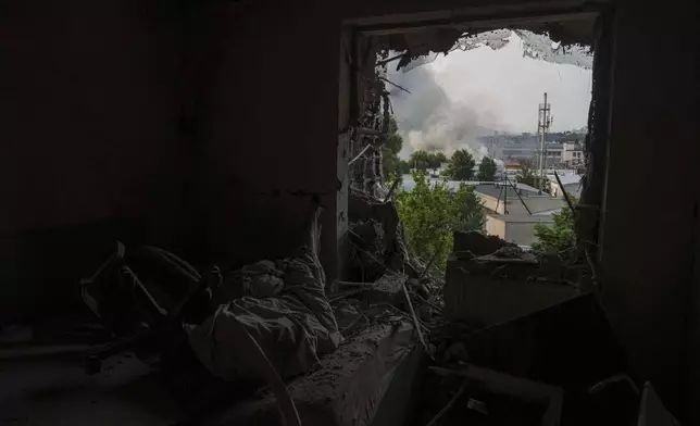 A smoke is seen from a window of apartments damaged by a Russian drone strike on Kyiv, Ukraine, Tuesday, June 10, 2025. (AP Photo/Evgeniy Maloletka)
