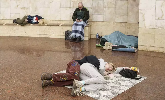 Couple sleep on a floor as they take cover at a metro station during a Russian drone strike on Kyiv, Ukraine, Tuesday, June 10, 2025. (AP Photo/Evgeniy Maloletka)