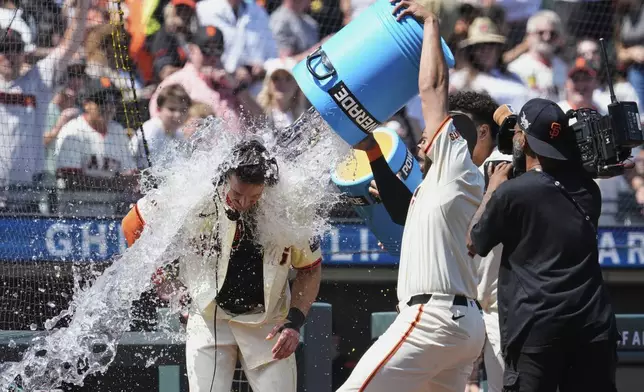 San Francisco Giants' Matt Chapman, left, is doused with water by Dominic Smith, second from right, after hitting a game-wining, two-run home run against the Atlanta Braves in the ninth inning of a baseball game Saturday, June 7, 2025, in San Francisco. (AP Photo/Godofredo A. Vásquez)
