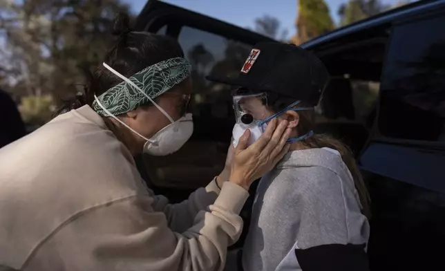 FILE - Eaton Fire evacuee Alyson Granaderos, left, sobs while trying to comfort her son, Ceiba Phillips, 11, as he visits their home for the first time since the fire in Altadena, Calif., Feb. 8, 2025. (AP Photo/Jae C. Hong, File)