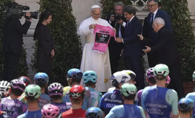 Pope Leo XIV receives a pink jersey from the hands of RCS president Urbano Cairo before the official start of the final stage of the Giro d'Italia cycling race, inside the Vatican, Sunday, June 1, 2025. (AP Photo/Andrew Medichini)