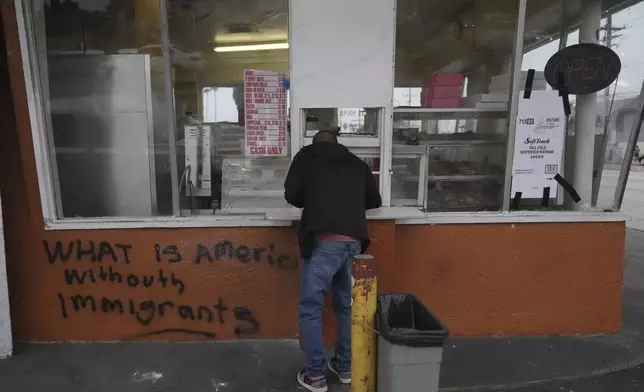 A man views a vandalized donut shop Sunday, June 8, 2025, in Compton, Calif., following an immigration raid protest the night before. (AP Photo/Jae Hong)