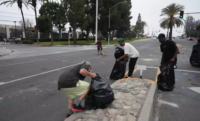 Local parishioners clean up the streets Sunday, June 8, 2025, in Paramount, Calif., following an immigration raid protest the night before. (AP Photo/Jae Hong)