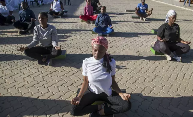 Community members sit on the floor and meditate in a yoga class at Socialite Bar in Chitungwiza on the outskirts of Harare, Zimbabwe, Saturday, June 14, 2025. (AP Photo/Aaron Ufumeli)