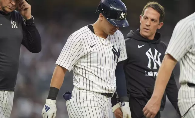A trainer and manager Aaron Boone, left, check on Anthony Volpe after Volpe was hit by a pitch during the second inning of a baseball game against the Boston Red Sox, Friday, June 6, 2025, in New York. (AP Photo/Frank Franklin II)