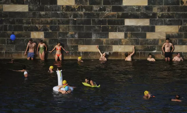People swim in the river Spree to demand the lift of the hundred years old swimming ban at the river in Berlin, Germany, Tuesday, June 17, 2025. (AP Photo/Markus Schreiber)