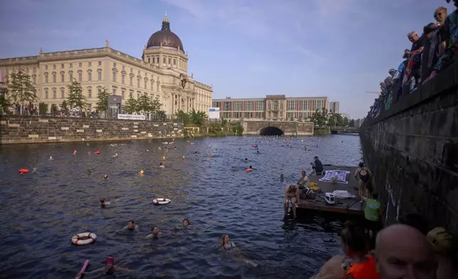 People swim in the river Spree to demand the lift of the hundred years old swimming ban at the river in front of the Stadtschloss or City Place in Berlin, Germany, Tuesday, June 17, 2025. (AP Photo/Markus Schreiber)