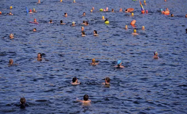 People swim in the river Spree to demand the lift of the hundred years old swimming ban at the river in Berlin, Germany, Tuesday, June 17, 2025. (AP Photo/Markus Schreiber)