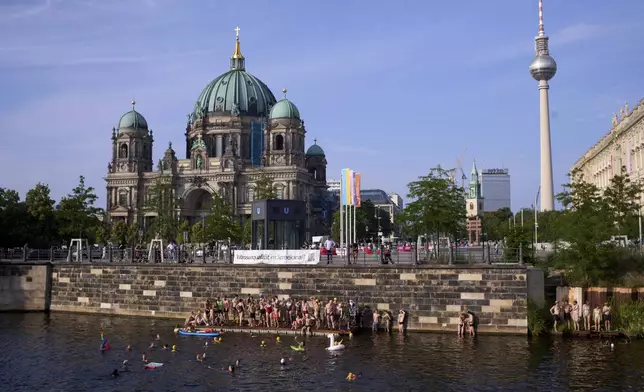 People swim in the river Spree to demand the lift of the hundred years old swimming ban at the river in Berlin, Germany, Tuesday, June 17, 2025. (AP Photo/Markus Schreiber)
