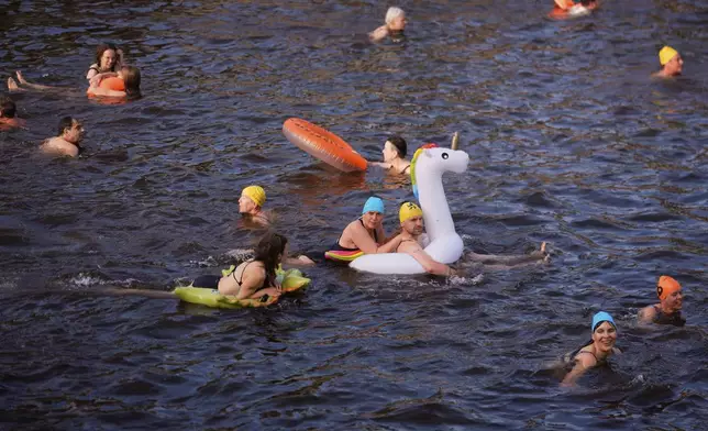 People swim in the river Spree to demand the lift of the hundred years old swimming ban at the river in Berlin, Germany, Tuesday, June 17, 2025. (AP Photo/Markus Schreiber)