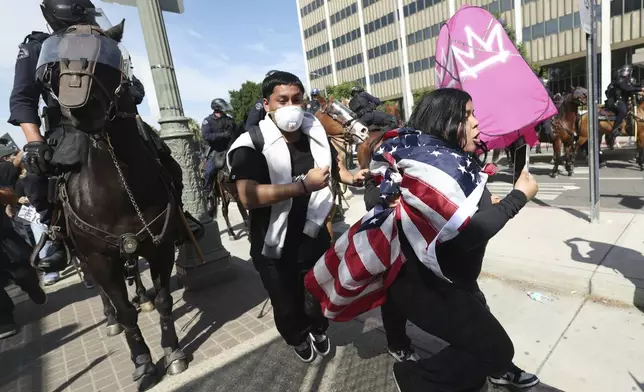 Law enforcement on horseback disperse demonstrators during a protest Saturday, June 14, 2025, in Los Angeles. (AP Photo/Ethan Swope)