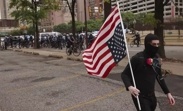 A protestor walks through downtown Philadelphia with an upside down American flag, Saturday, June 14, 2025. (AP Photo/Yuki Iwamura)