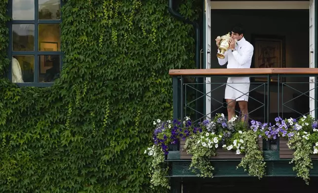 FILE - Carlos Alcaraz of Spain kisses his trophy on the balcony of Centre Court for the crowds gathered below after defeating Novak Djokovic of Serbia in the men's singles final at the Wimbledon tennis championships in London, Sunday, July 14, 2024. (AP Photo/Kirsty Wigglesworth,File)