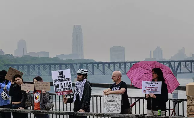 Demonstrators hold signs during a protest against recent immigration raids on the Lake Street-Marshall Bridge on Wednesday, June 11, 2025, in Minneapolis, Minn. (Kerem Yücel/Minnesota Public Radio via AP)