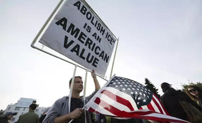 People hold up signs during a protest against federal immigration arrests, Wednesday, June 11, 2025, in Seattle. (AP Photo/Ryan Sun)