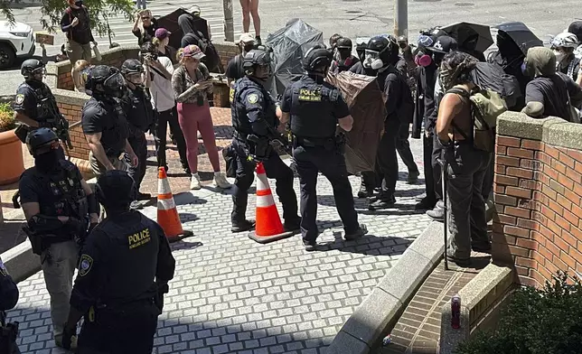 Protesters face off with officers with Federal Protective Service outside a blocked exit at the Immigration Court on Tuesday, June 10, 2025, in Seattle. (AP Photo/Martha Bellisle)
