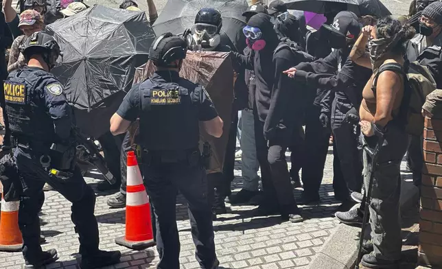 Protesters face off with officers with Federal Protective Service outside a blocked exit at the Immigration Court on Tuesday, June 10, 2025, in Seattle. (AP Photo/Martha Bellisle)