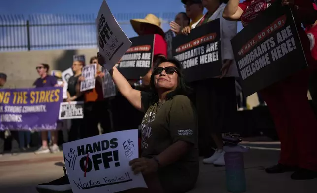 Adriana Martinez holds up signs during a rally of union workers and others for David Huerta, the president of Service Employees International Union California, Monday, June 9, 2025, in Las Vegas. (AP Photo/John Locher)