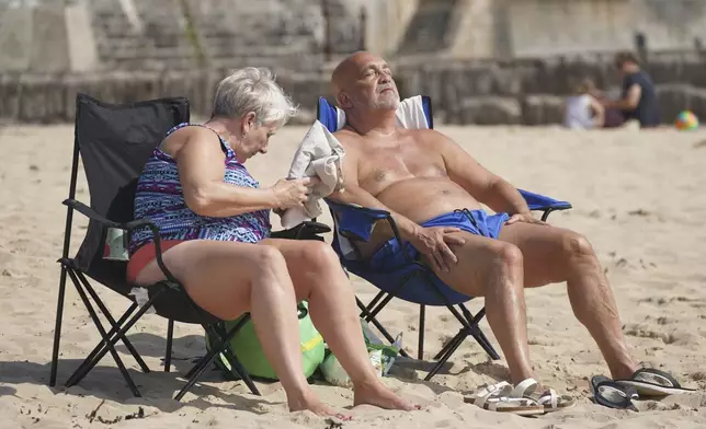 People enjoy the hot weather at Cullercoats Beach in North Shields, England, Friday, June 20, 2025. (Owen Humphreys/PA via AP)