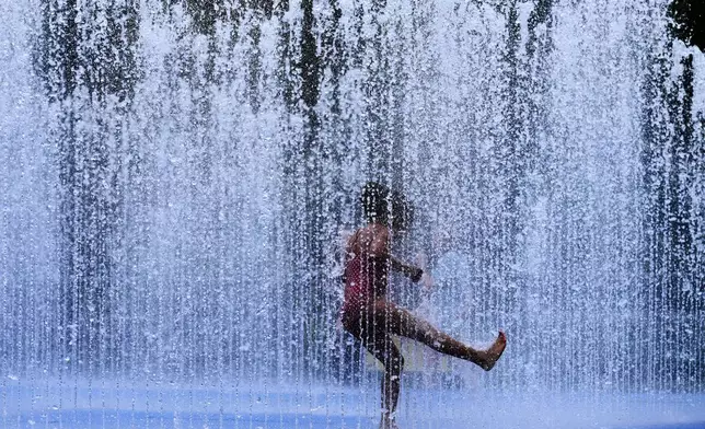 A child plays in a fountain in London, as a heatwave passes through the capital, Friday, June 20, 2025. (AP Photo/Kirsty Wigglesworth)