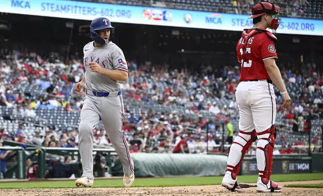Texas Rangers' Josh Smith, left, comes in to score on a ground out by Marcus Semien as Washington Nationals catcher Riley Adams looks on at right during the fifth inning of a baseball game, Sunday, June 8, 2025, in Washington. (AP Photo/Nick Wass)