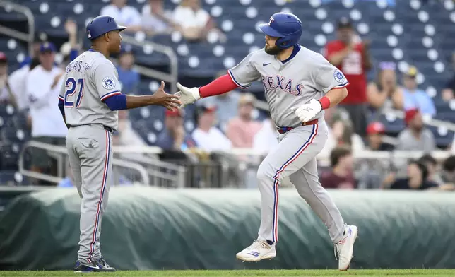 Texas Rangers' Jake Burger celebrates his home run with third base coach Tony Beasley (27) as he round the bases during the eighth inning of a baseball game against the Washington Nationals, Sunday, June 8, 2025, in Washington. (AP Photo/Nick Wass)