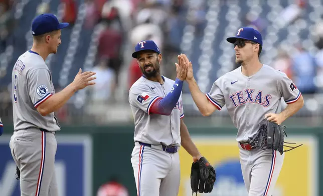 Texas Rangers' Corey Seager, left, Marcus Semien, center, and Evan Carter, right, celebrate after a baseball game against the Washington Nationals, Sunday, June 8, 2025, in Washington. (AP Photo/Nick Wass)