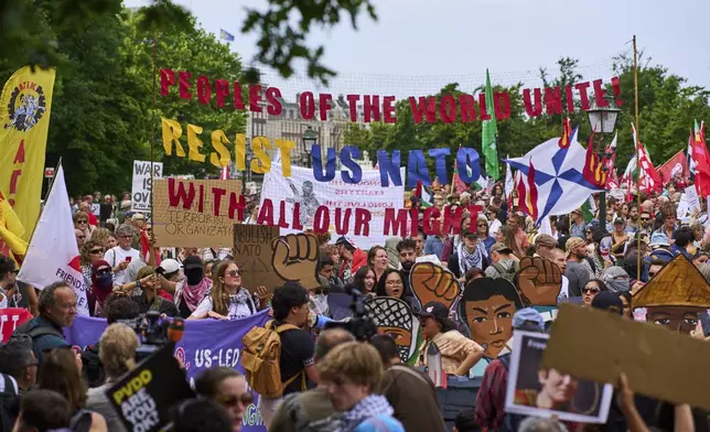 People hold banners during a demonstration ahead of the NATO summit in The Hague, Netherlands, Sunday, June 22, 2025. (AP Photo/Peter Dejong)