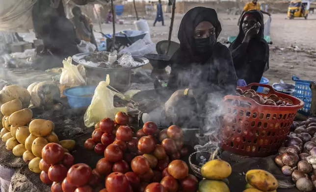 Sudanese women sell fruits and vegetables in the Adre, Chad, transit camp, Tuesday, May 6, 2025. (AP Photo/Caitlin Kelly)