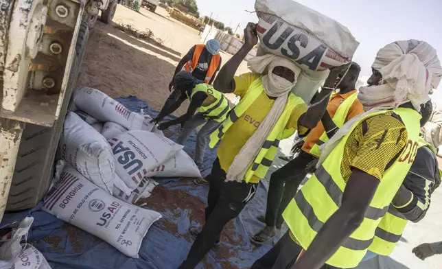 Bags of food aid are offloaded before distribution in the Adre, Chad, transit camp, Thursday, May 8, 2025. (AP Photo/Caitlin Kelly)