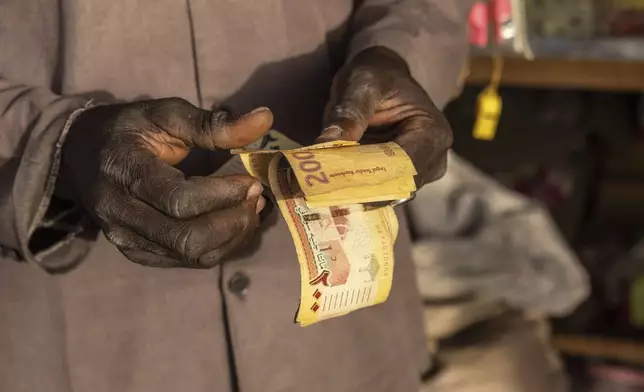 Refugees barter and sell goods using Sudanese pounds in the Adre, Chad, transit camp, Tuesday, May 6, 2025. (AP Photo/Caitlin Kelly)