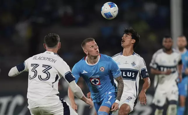 Mateusz Bogusz of Mexico's Cruz Azul, center, competes for the ball against Mathias Laborda, right, and Tristan Blackmon of Canada's Vancouver Whitecaps during the CONCACAF Champions Cup final soccer match in Mexico City, Sunday, June 1, 2025. (AP Photo/Fernando Llano)