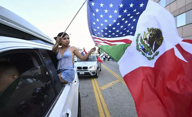 A girl waves an American and Mexican flag during a protest outside the Federal Building, Thursday, June 12, 2025, in Los Angeles. (AP Photo/Wally Skalij)