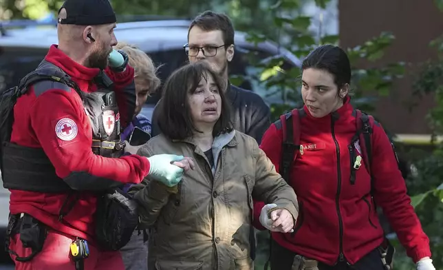 Medical workers help a woman in the yard of an apartment building destroyed after a Russian attack in Kyiv, Ukraine, early Monday, June 23, 2025. (AP Photo/Efrem Lukatsky)